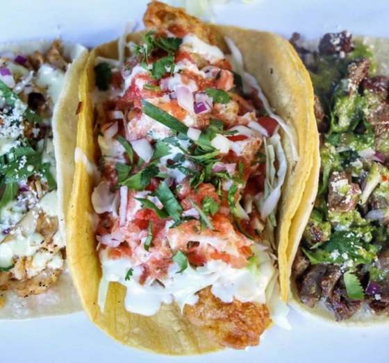 Three Baja tacos on corn tortillas with cabbage, salsa and crema